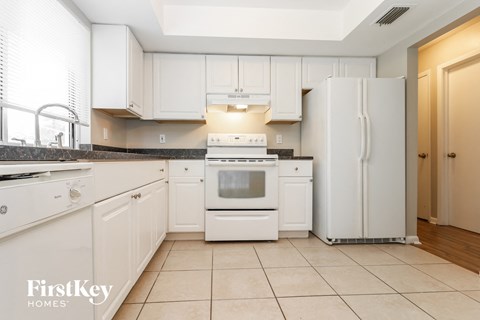 A kitchen with white appliances and cabinets.