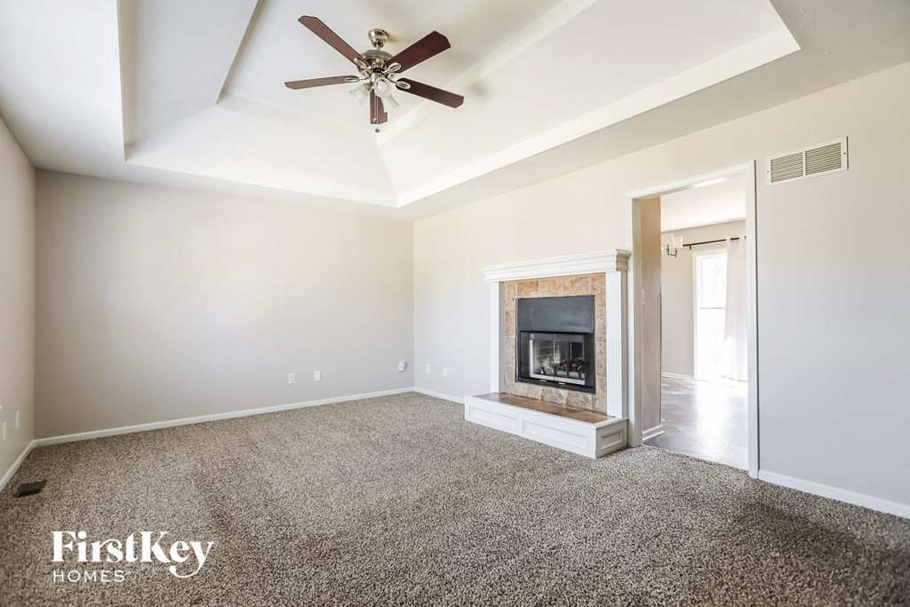 a living room with a fireplace and a ceiling fan