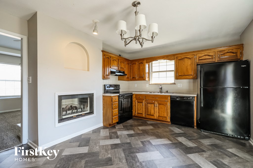 a kitchen with a fireplace and wooden cabinets and black appliances