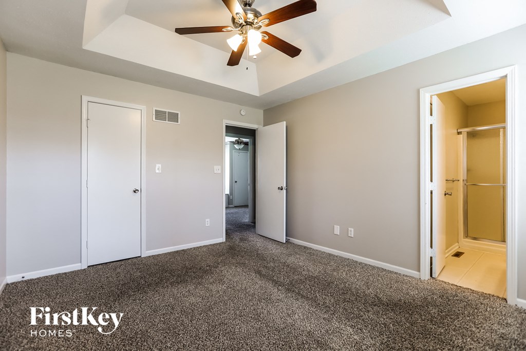 a master bedroom with carpet and a ceiling fan