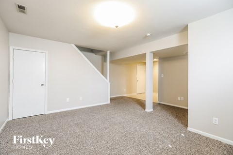 a living room with white walls and carpet and a door to a closet