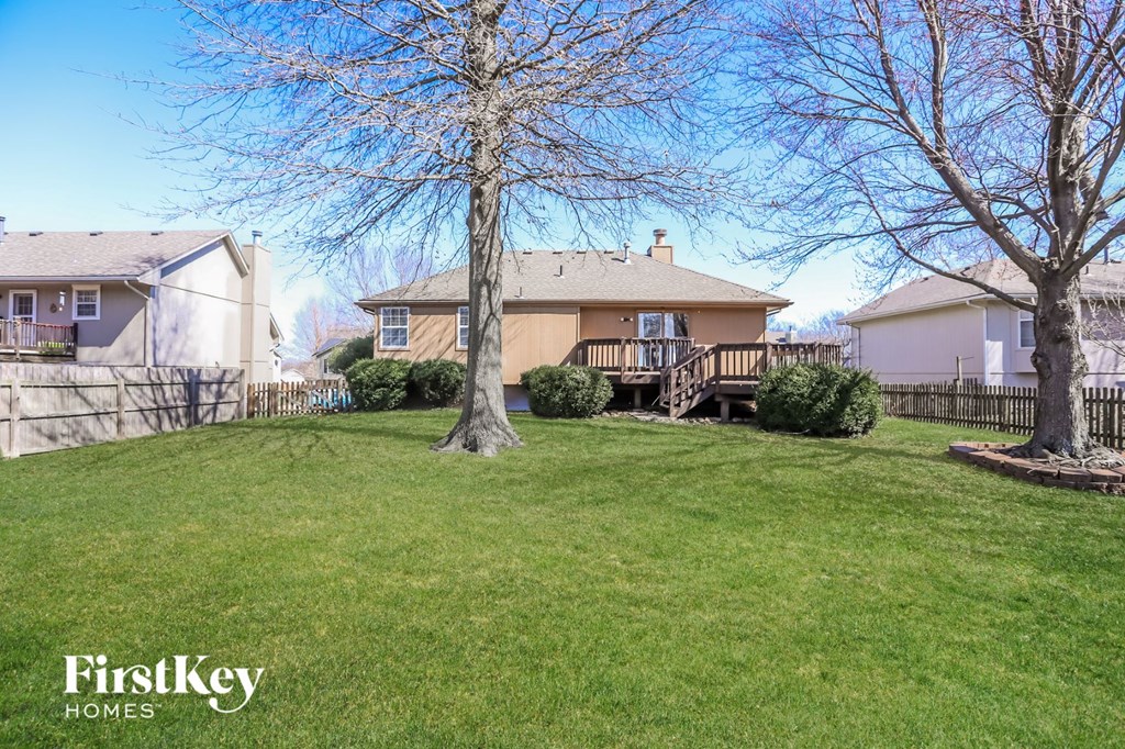 a yard with two trees and a house with a deck