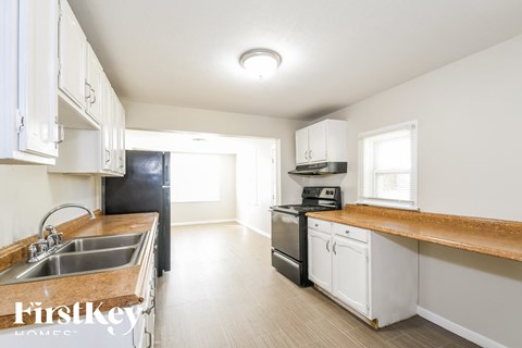 a kitchen with white cabinets and white appliances and wood counter tops