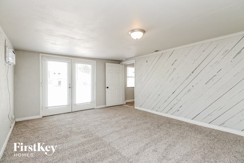 A sparsely furnished room with a carpeted floor and a wooden wall.