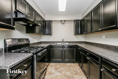 A kitchen with black cabinets and a marble countertop.