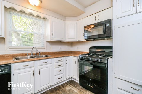 A kitchen with a black oven and white cabinets.