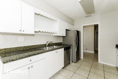 a kitchen with white cabinets and a sink and a refrigerator