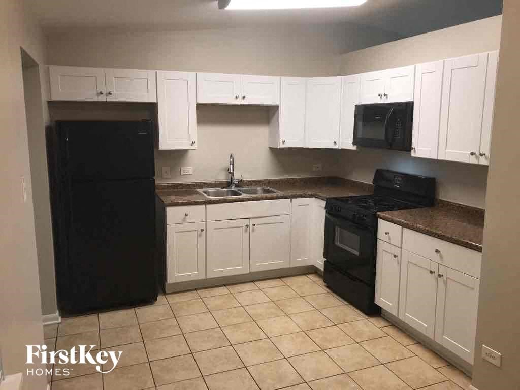 an empty kitchen with white cabinets and black appliances