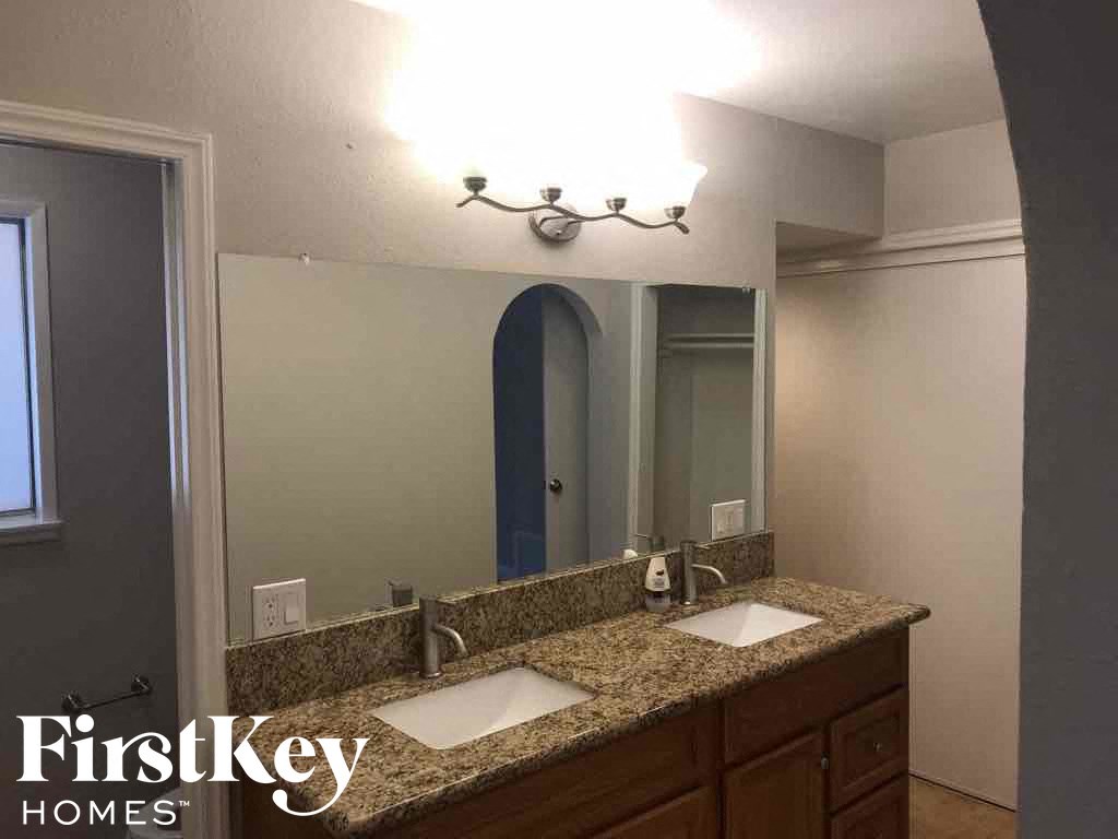 a bathroom with a counter with two sinks and a mirror