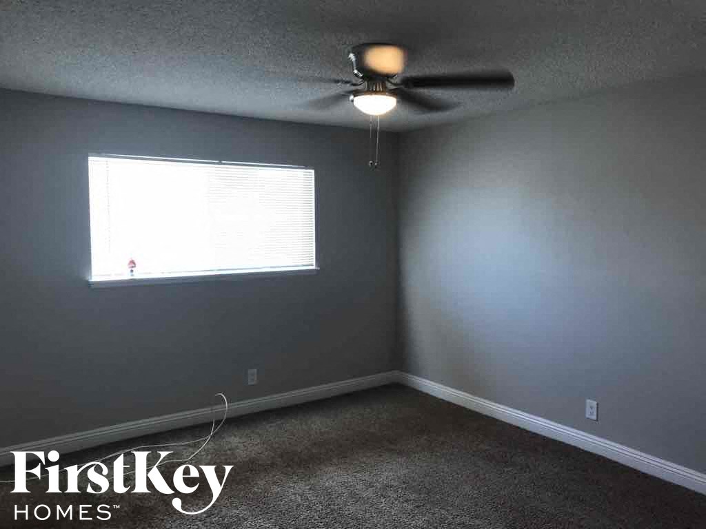 an empty room with a ceiling fan and a window