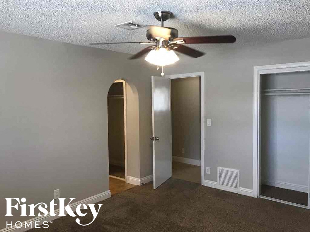 an empty room with a ceiling fan and two doors