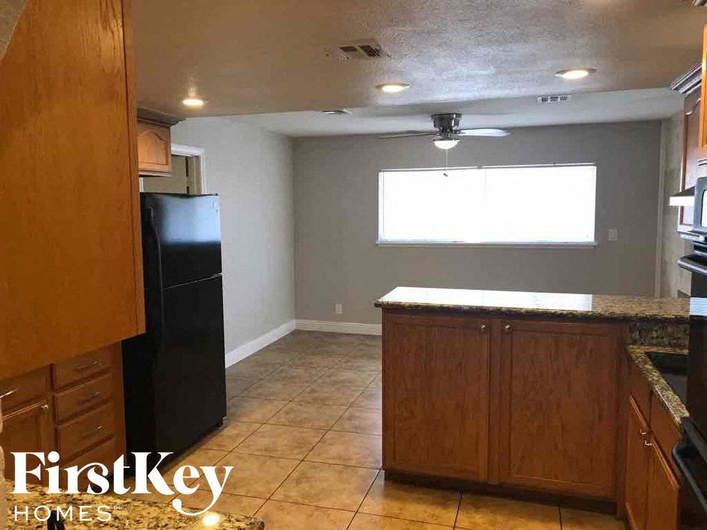 an empty kitchen with a black refrigerator and a window