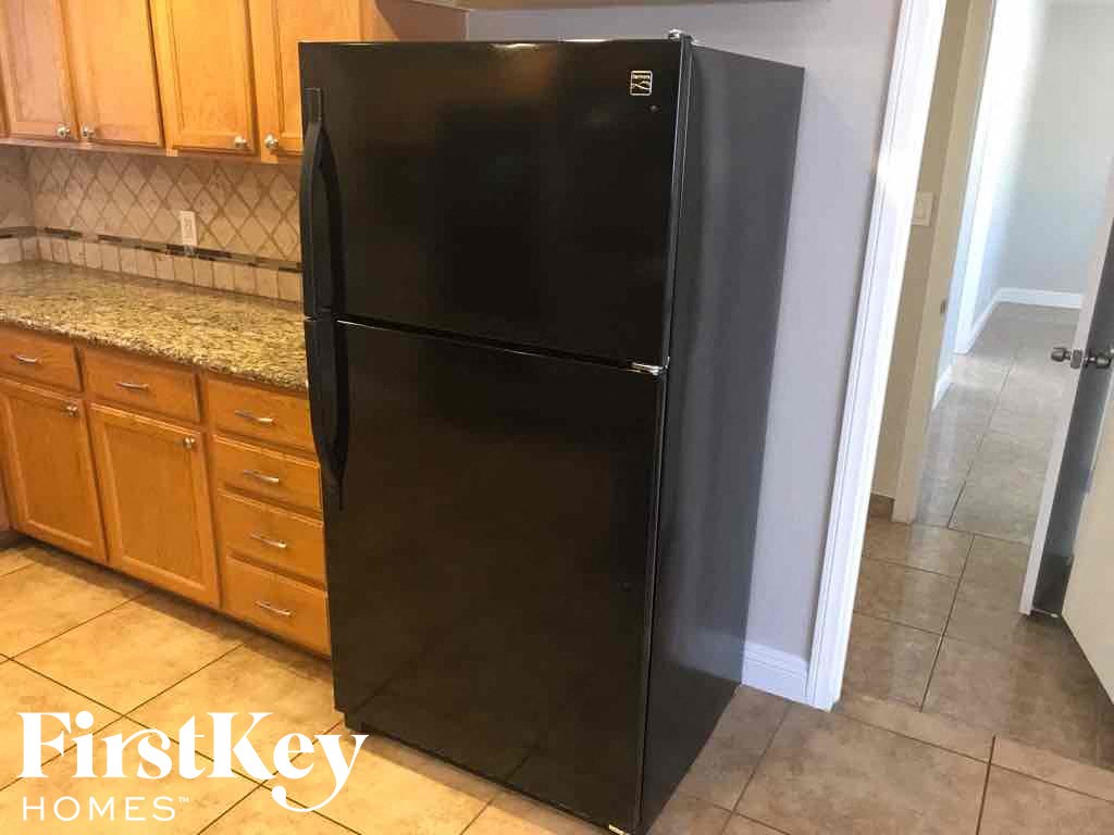 a black refrigerator in a kitchen with cabinets