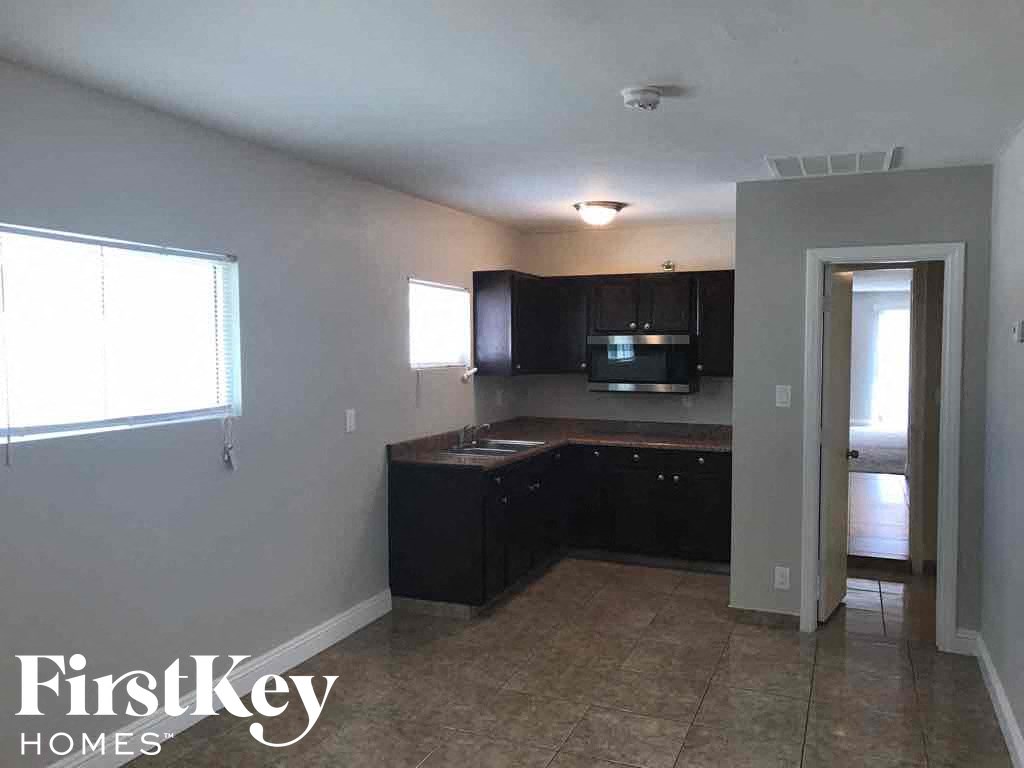 an empty kitchen with black cabinets and tile flooring