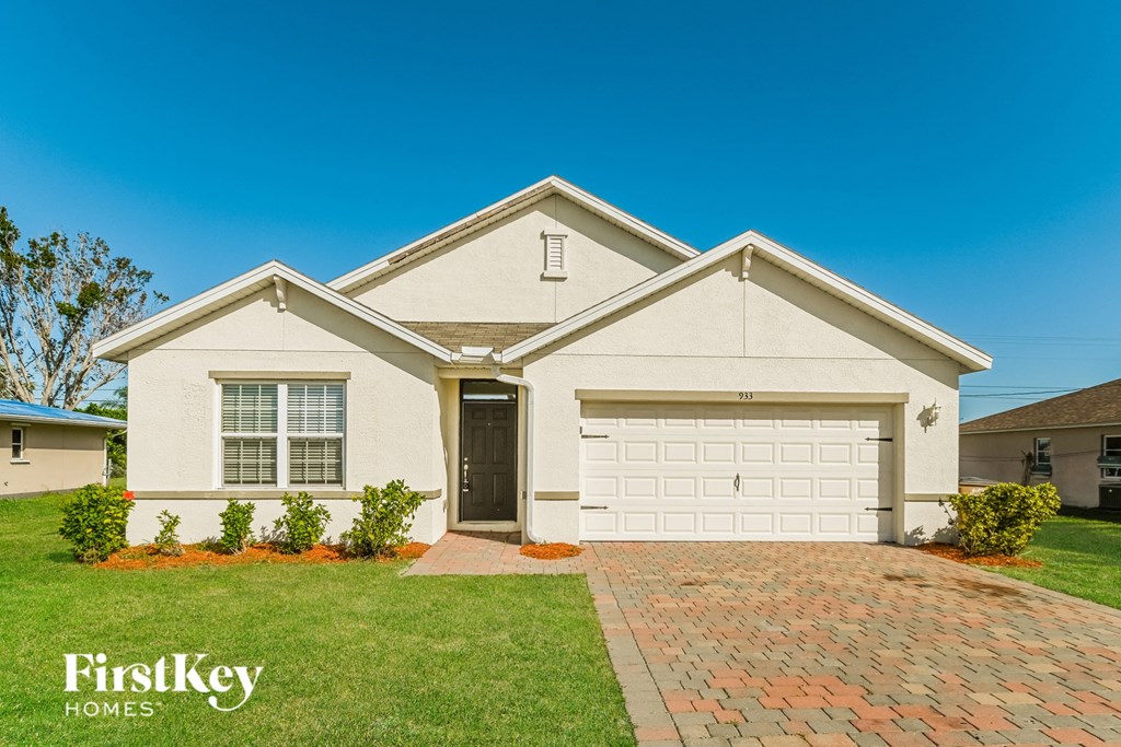 a white house with a garage door and a lawn