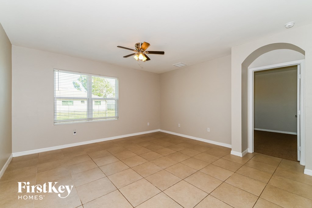 an empty living room with a ceiling fan and a door to a closet