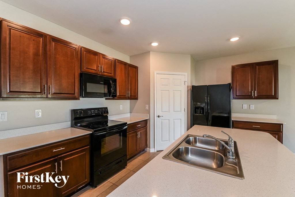 a kitchen with black appliances and white counter tops and wooden cabinets
