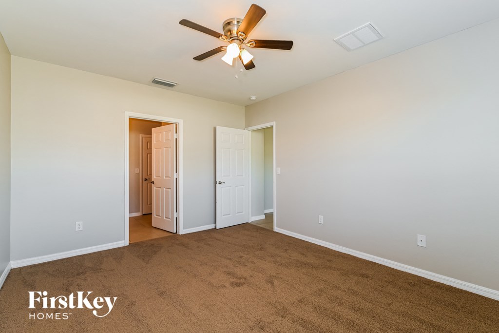 a living room with a ceiling fan and a carpet