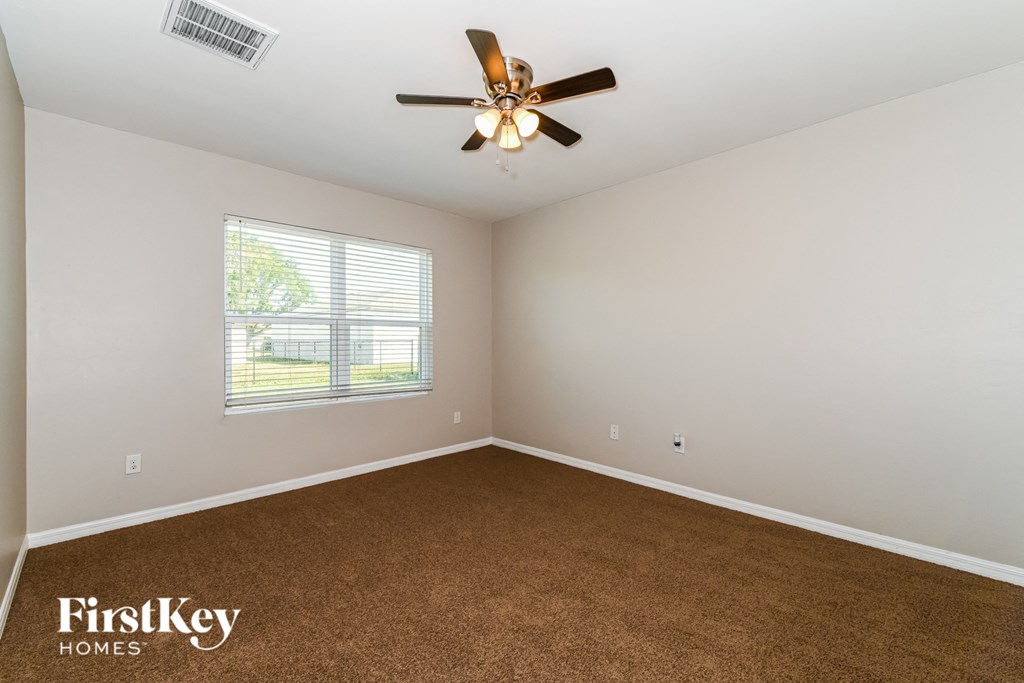 an empty room with a ceiling fan and a window