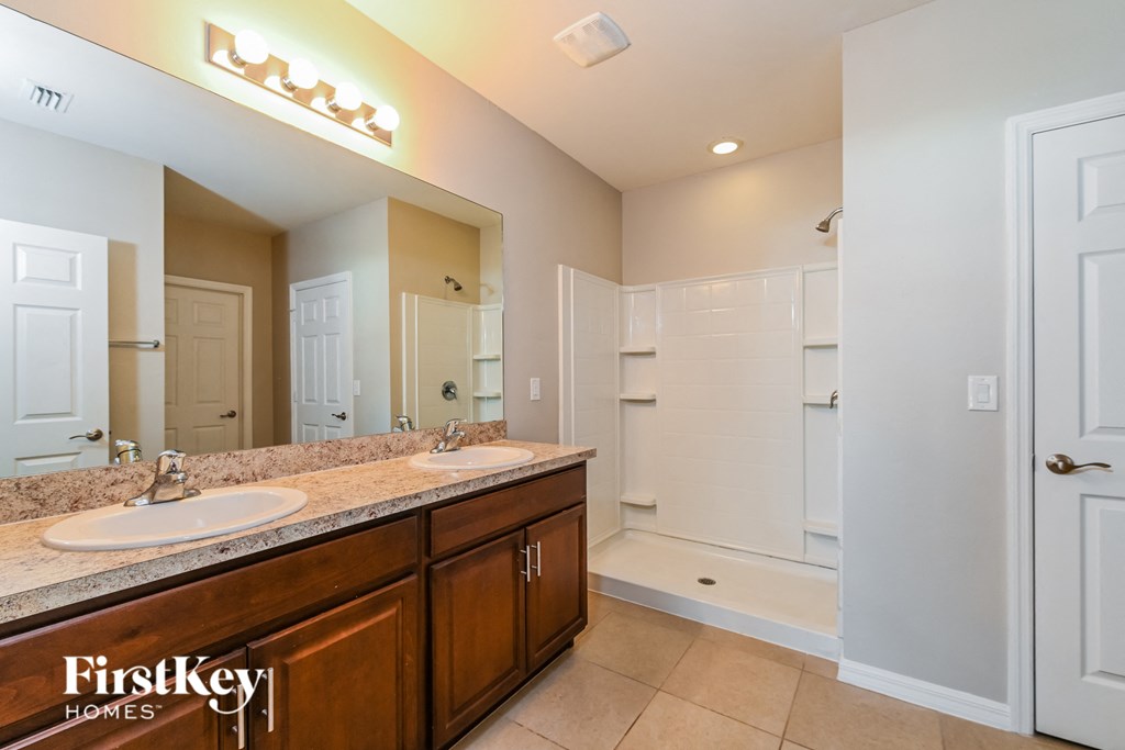 the master bathroom has dual sinks and a large mirror