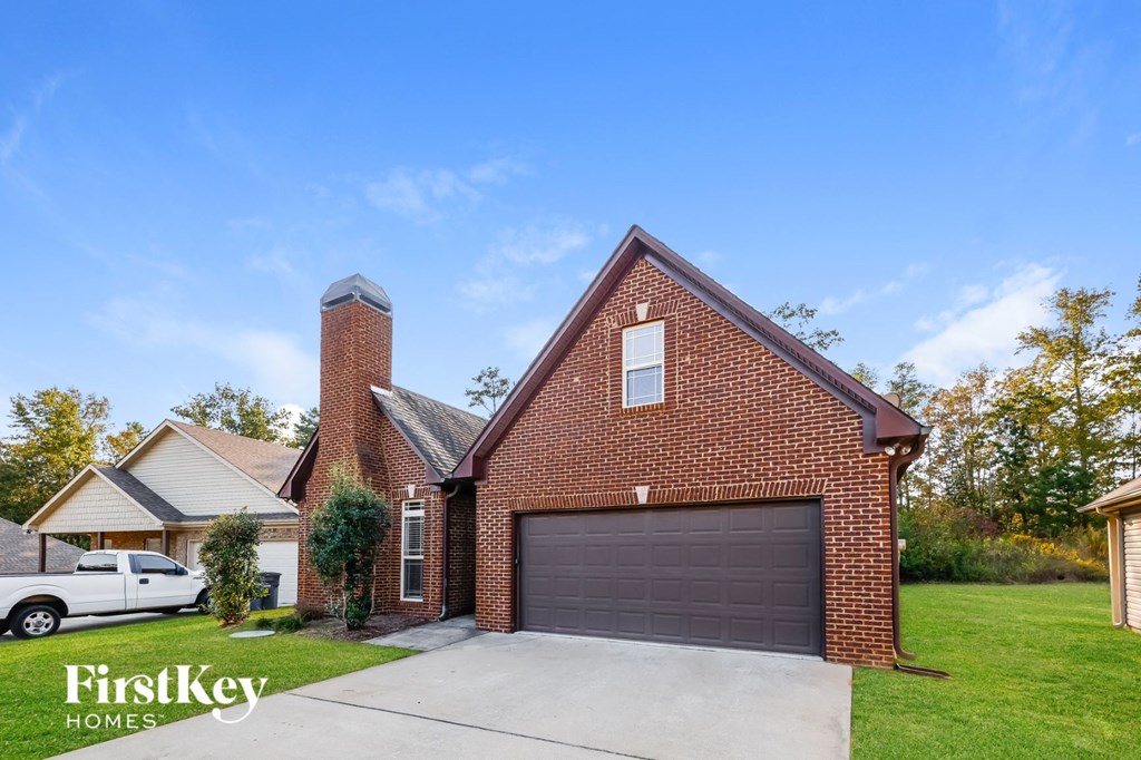 A brick house with a garage door is for sale.