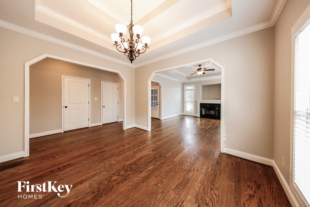 A large empty room with wooden floors and a chandelier.