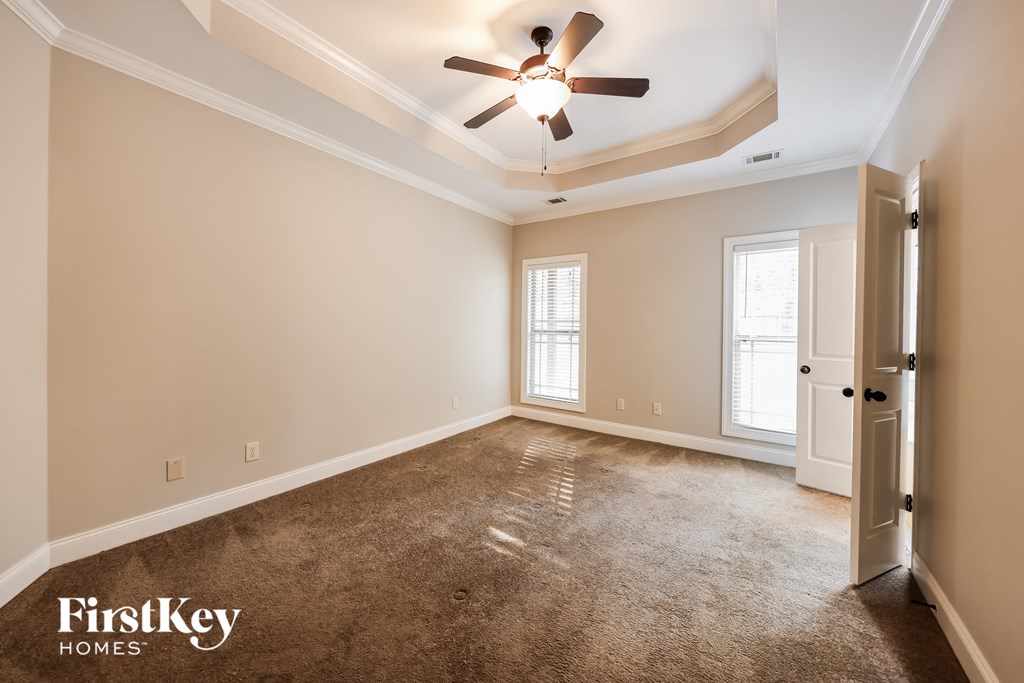 A spacious room with a ceiling fan and a door on the right side.