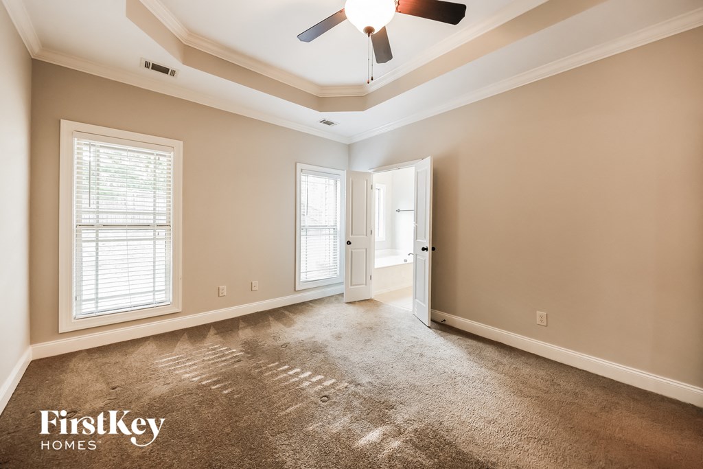 A room with a carpeted floor and a ceiling fan.