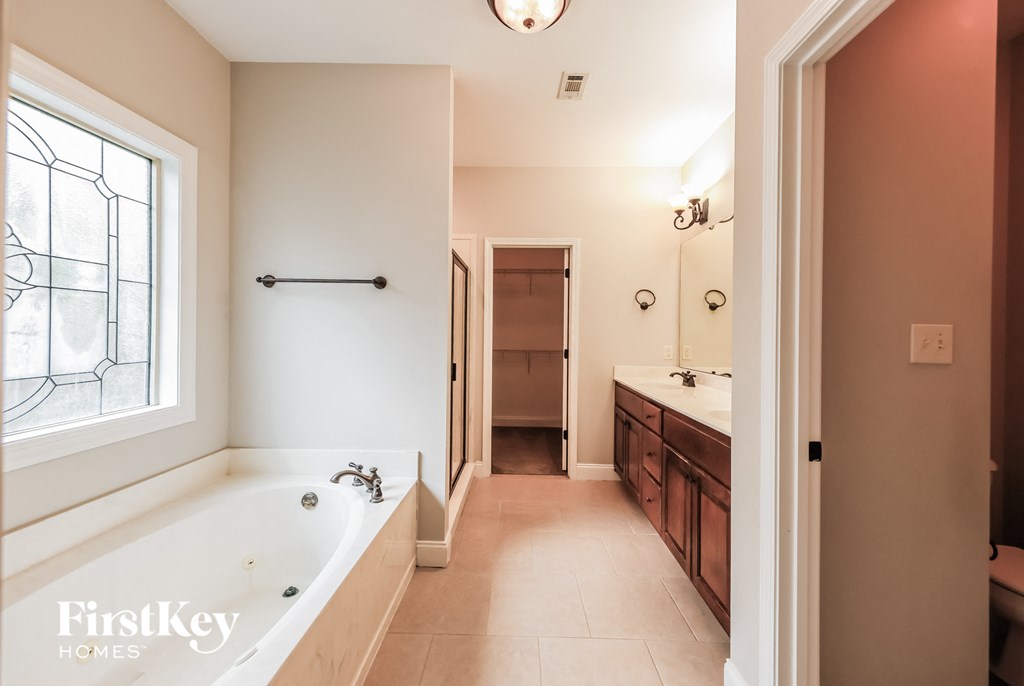 A bathroom with a tub, sink, and a window.