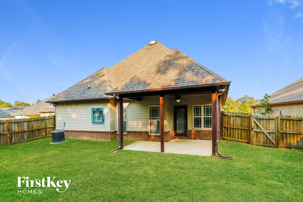 A house with a covered patio and a fence in the background.
