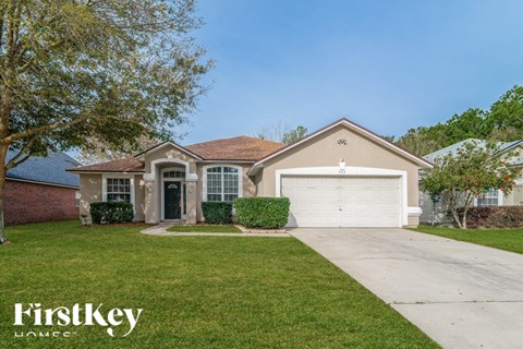 a beige house with a white garage door and a lawn