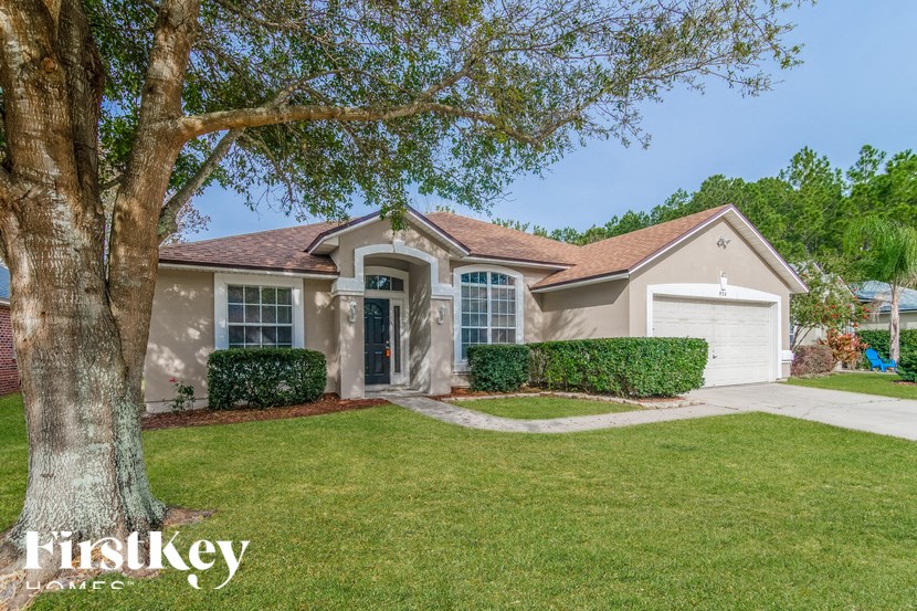 a beige house with a large tree in front of it