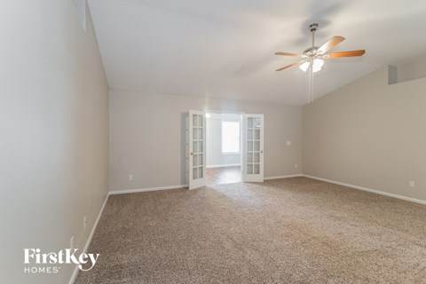 a spacious living room with carpet and a ceiling fan