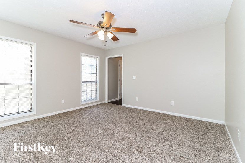 an empty living room with a ceiling fan and a window