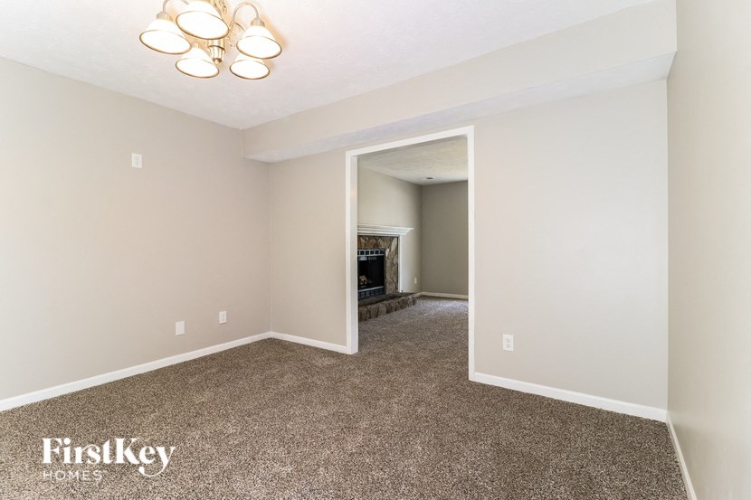 a living room and dining room with carpeting and a fireplace