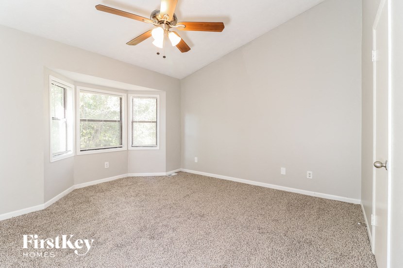 an empty room with a ceiling fan and a window