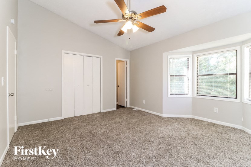 an empty living room with a ceiling fan and a window