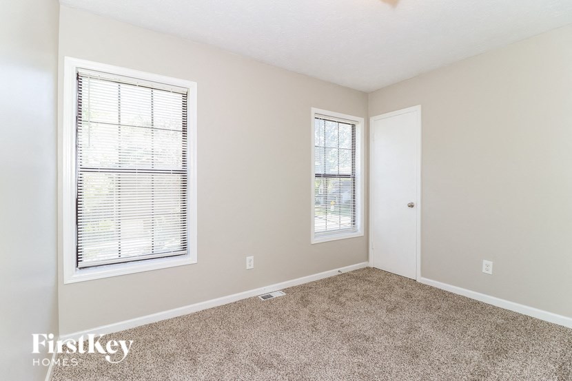 a bedroom with two windows and a carpeted floor