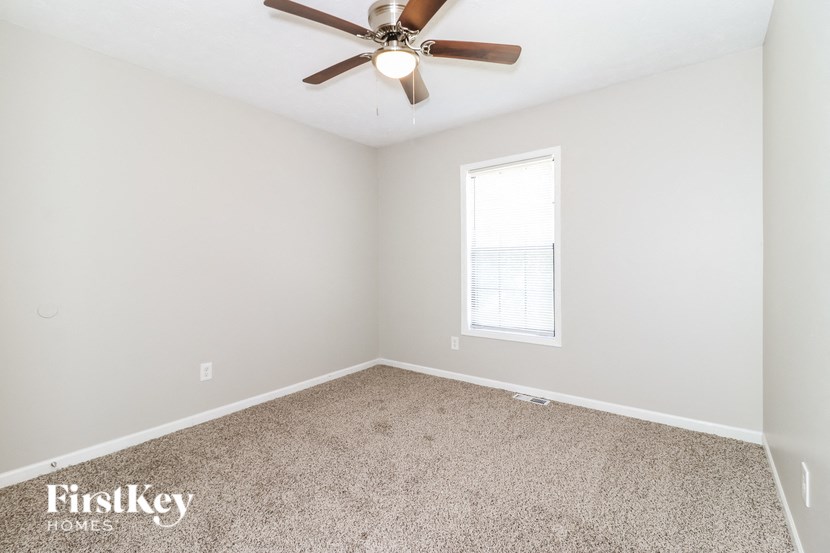 an empty room with a ceiling fan and a window