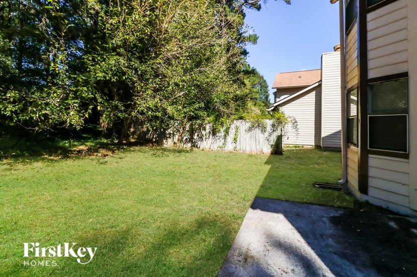 the backyard of a house with a lawn and a tree