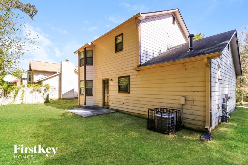 the back of a yellow house with a yard and a cage