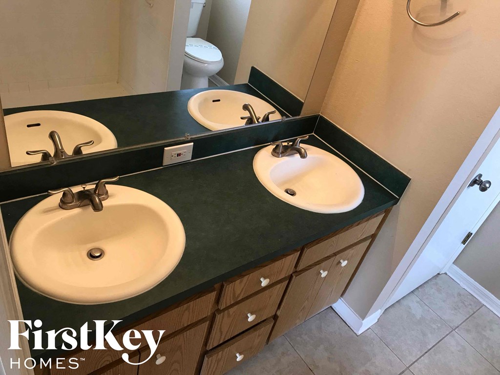 a bathroom with three sinks and a toilet