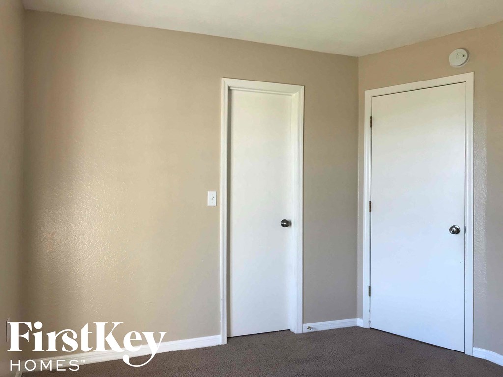 an empty room with two white doors and a carpet