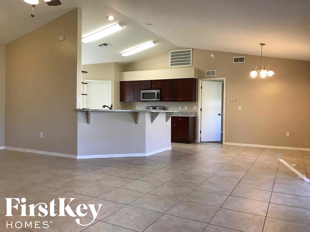 an empty living room with a kitchen and tile floor