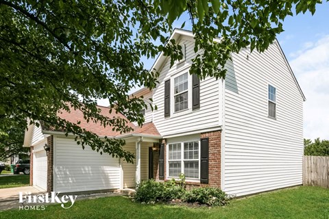 a white house with white siding and a tree