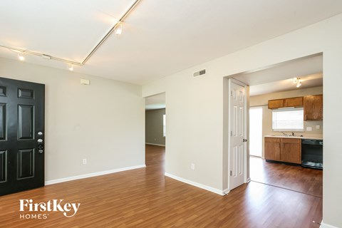 a living room and kitchen with wood flooring and a black door