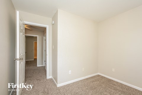 a bedroom with white walls and carpet and a door to a hallway