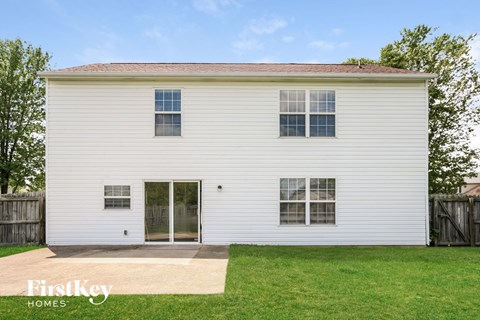 the back of a white house with a yard and grass