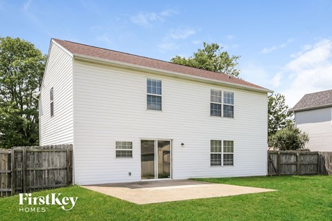 the outside of a white barn with a yard and a wooden fence