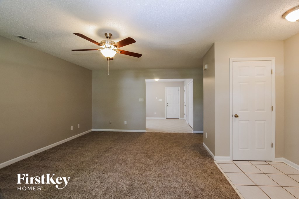 an empty living room with a ceiling fan and a white door